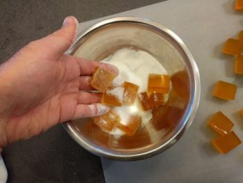 Enrober chaque cube de la pâte de fruits à la passion avec du sucre