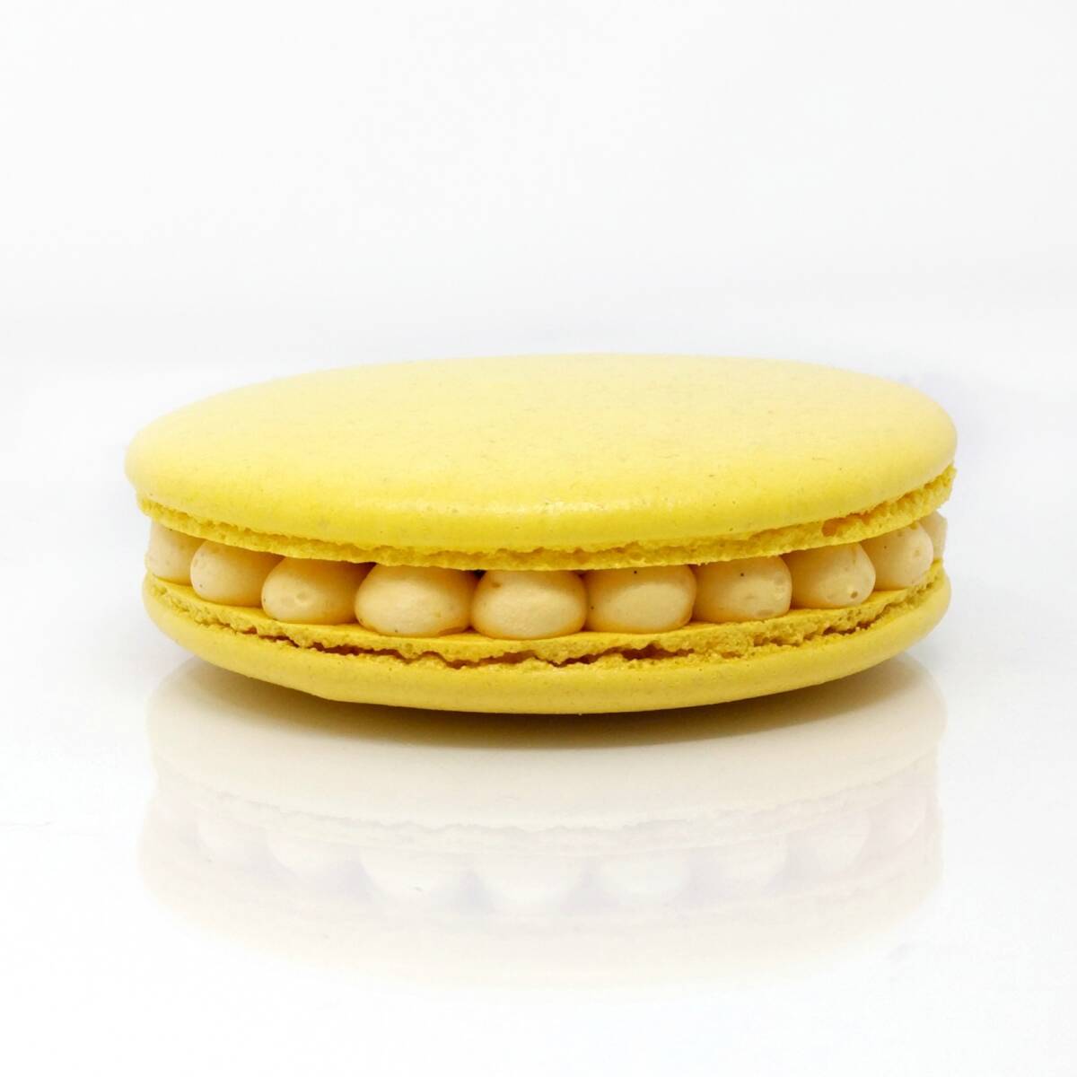 Gros macaron individuel fourré d'une crème diplomate au fruit de la passion et de morceaux d'ananas crus et caramélisés