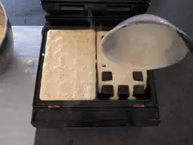 Pâte dans le gaufrier prêt à cuire