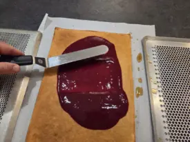 Étaler une couche de confit de framboise, éventuellement raffermie au congélateur