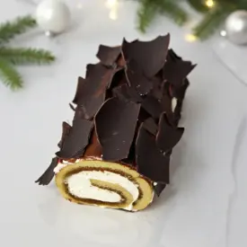 bûche tiramisu roulée décorée de chocolat noir, ambiance Noël lumineuse
